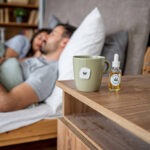 CBD oil and cannabis tea on bedside table with couple resting